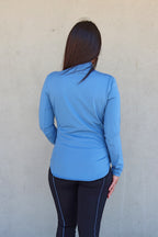 Vista de la espalda de la sudadera ajustada "Magnolia" de Vima Studio en azul combinada con el legging Dalia negro con vivos azules.