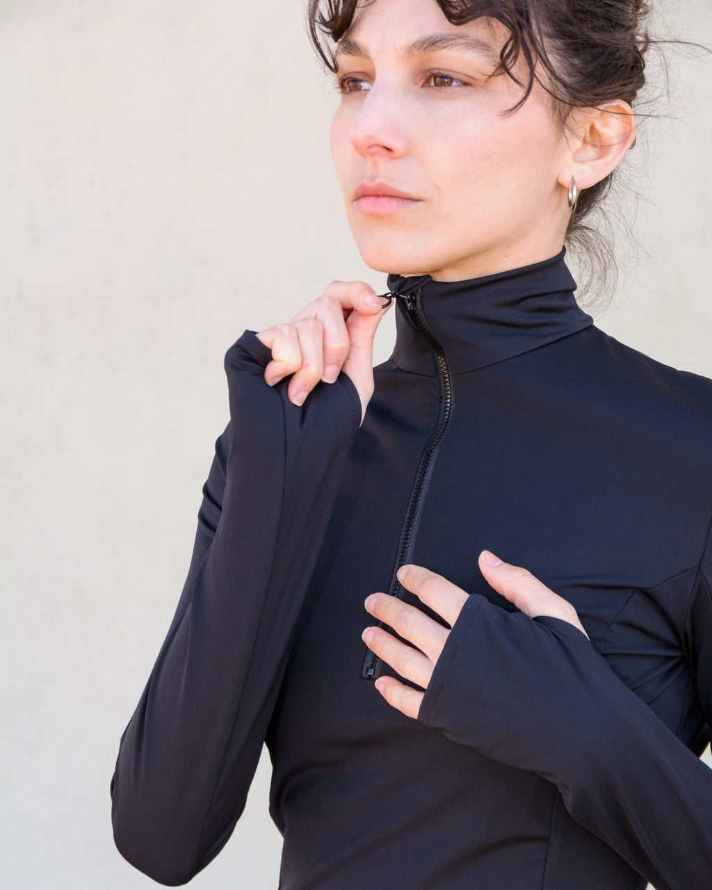 Detalles del cuello alto con cremallera y manga con hueco para el pulgar de la sudadera negra, segunda piel de Vima Studio.