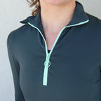 Detalle de la cremallera a contraste de la sudadera Magnolia en verde de Vima studio. Cuello alto abierto.