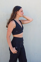 Perfil del sujetador deportivo Girasol. Prenda reversible en verde y negro con escote en V, logo en el lateral y goma en la cinturilla.