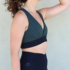 Lateral del sujetador deportivo Girasol de Vima Studio. Prenda reversible en verde y negro. Escote en v, con goma en la cinturilla.