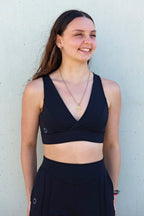 Sujetador deportivo Girasol de Vima Studio. Prenda reversible en negro y verde con escote en v y goma en la cinturilla.
